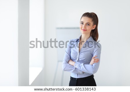 Portrait of young beautiful business woman in the office. Crossed arms Royalty-Free Stock Photo #601338143