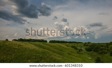 Rural landscape in hilly terrain with rain clouds. Ukraine. Europe.