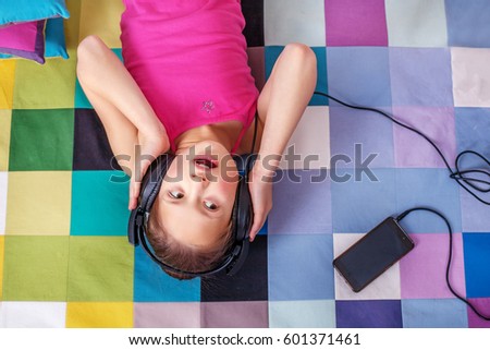 Child student listening to an audiobook on headphones.  The concept of learning, music, childhood