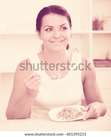 Young brunette woman at home eating breakfast cereal