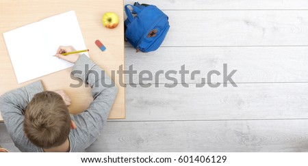 top view header of boy working behind school desk in classroom Royalty-Free Stock Photo #601406129
