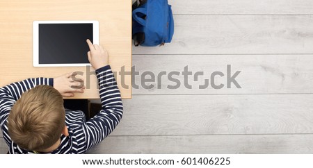 top view header of boy working behind school desk on tablet pc Royalty-Free Stock Photo #601406225