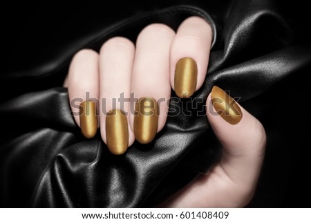 Golden manicure. Black silk or leather background Royalty-Free Stock Photo #601408409