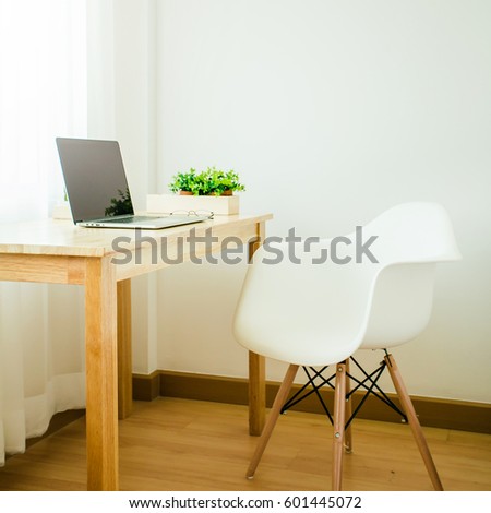 workspace with wood desk and white designer chair arranged as a part of a very bright living room