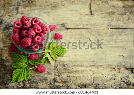 Ripe sweet raspberries in bowl on wooden table. Close up, top view, high resolution product