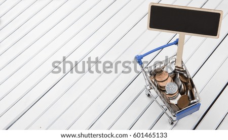 Concept image of retail commerce with miniature shopping cart and mini blackboard with Japanese coins over wooden background