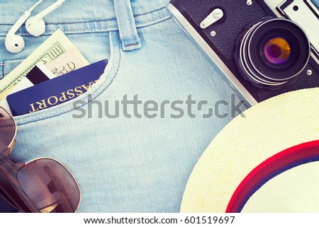 Vacation suite top view; Passport, dollar banknotes, credit card, headphones, sunglasses, hat, retro film photo camera on jeans. Travel top view background; Vintage filter