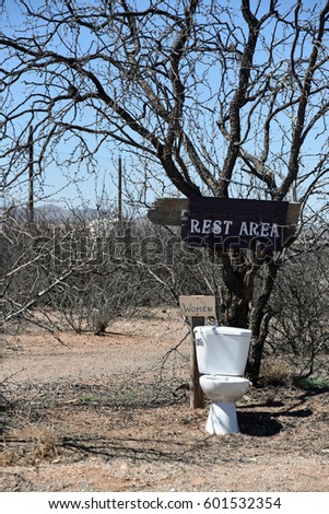 Toilet standing outdoors with a sign saying "Rest Area"