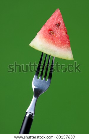 fork with a slice of watermelon on a green background