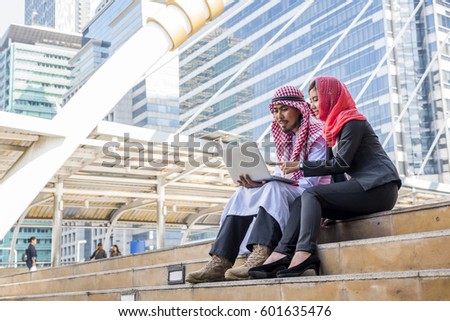 successful arabian business man and woman on staircase. Two arabian arab Muslim islamic people worker talk in city background. Engineer teamwork are talking about a building project in plan paper. 