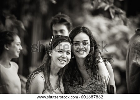 Group of young people having fun outside. Focus on beautiful young women posing for a picture. Black and white