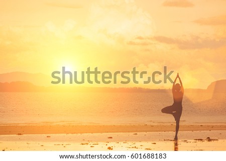 A woman practices yoga on a background of rocks, sea, beach and sky