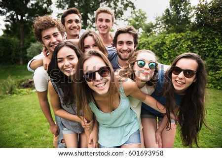 Group of young people standing in the grass, they pose for the photo smiling