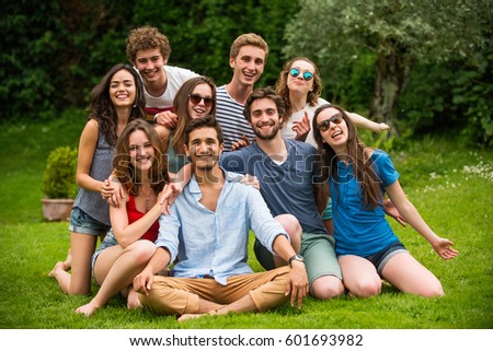 Group of young people sitting in the grass, they pose for the photo smiling