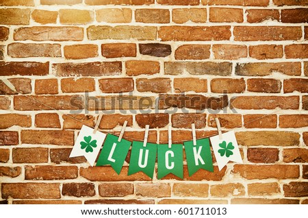 LUCK banner lettering on red, old orange brick wall background. Irish national colors St. Patrick's Day greeting card, postcard template. Space for copy, text.