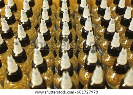 Many plastic bottles with caps with liquid for electronic cigarettes top view close up