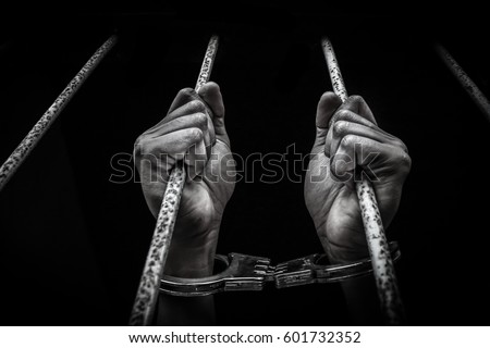 Hand of the prisoner on a steel lattice close up dark tone style Royalty-Free Stock Photo #601732352