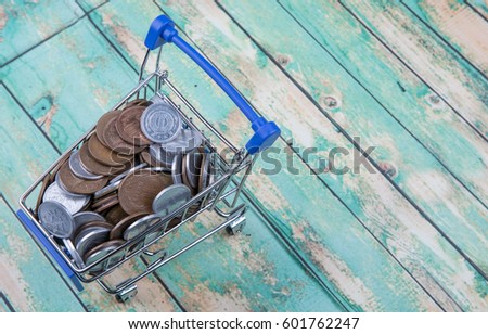 Concept image of retail commerce with miniature shopping cart with Japanese coins over wooden background