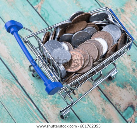 Concept image of retail commerce with miniature shopping cart with Japanese coins over wooden background