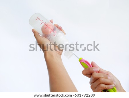 Mother hand washing baby milk bottle by bottle brush on white background Royalty-Free Stock Photo #601792289