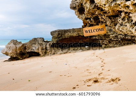 Welcome hanging banner on the rock with beach background. Bali, Indonesia.