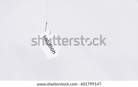 word solution on hanging white paper using fishing hook