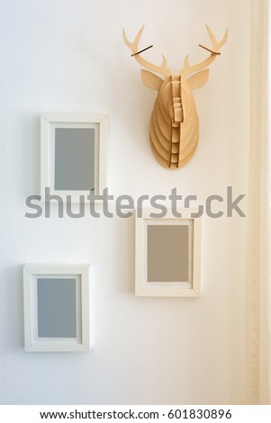 three empty picture frames on wall next to decorative fake antler