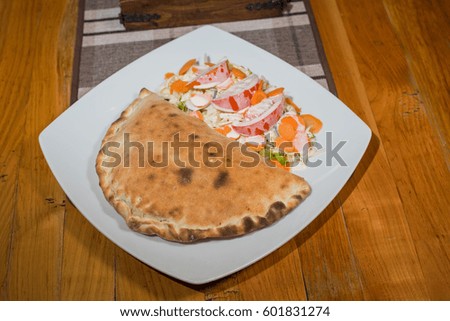 Delicious closed pizza with salad