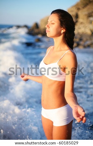 girl meditates standing in the surf.