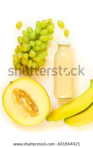 Glass bottle of melon, grapes, banana juice and ingredients isolated on white background. Top view. Vertical. Crop.