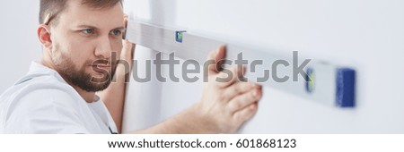 Builder checking wall with professional level, panorama