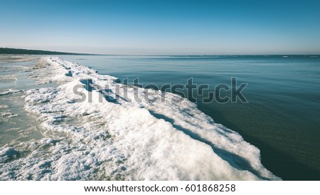 frozen beach in cold winters day with colorful sky and ice