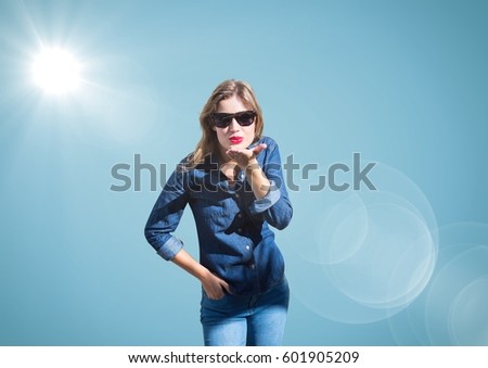 Digital composite of Woman blowing kiss against blue background with flare