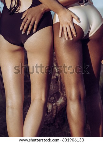 Two beautiful tanned young model on seaside in summer posing in swimsuit. African american europeon woman. Sea background. Black and white Body. Legs, Hends, Ass Spa.