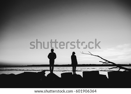 Man and woman stand separately on lake shore Royalty-Free Stock Photo #601906364
