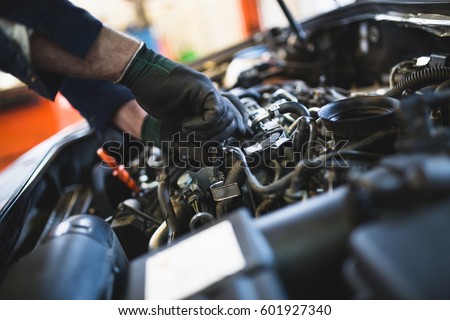 Close up hands of unrecognizable mechanic doing car service and maintenance. Royalty-Free Stock Photo #601927340