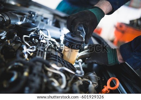 Close up hands of unrecognizable mechanic doing car service and maintenance. Oil and fuel filter changing. Royalty-Free Stock Photo #601929326
