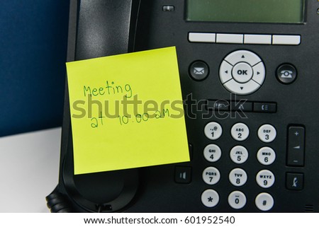 Paper note with meeting time at 10.00 AM wording is sticked on the IP Phone