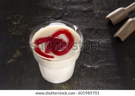 Delicious Pudding strawberry flavor in plastic cup for take away front of black rustic texture