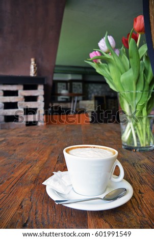 cup of cappuccino with spoon on the wooden table background