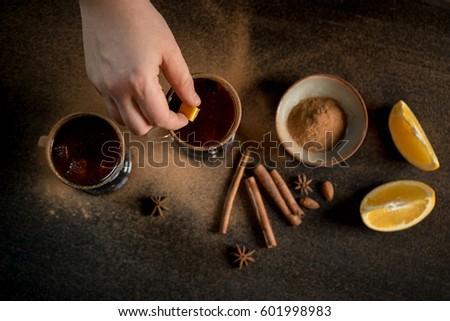 Mulled wine or grog tea to serve by barman hand. Dark black background for text area or design. Burning mulled wine with sparks, spice and orange. Horizontal photo. Flat top view, overhead.