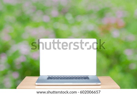 laptop with blank screen on wooden table outdoors and garden blurred background. Concept Online, freelancer working, communication , technology , shopping, banking