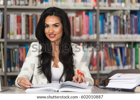 In The Library - Pretty Female Student With Laptop And Books Working In A High School Or University Library - Shallow Depth Of Field