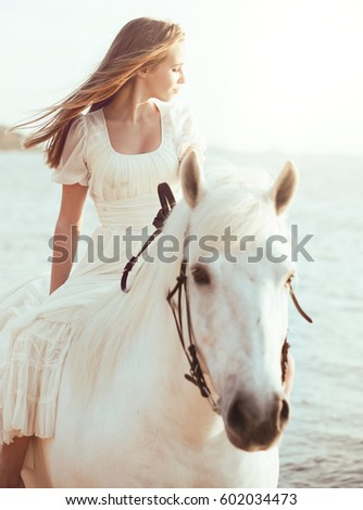 Girl in white dress with horse on the beach