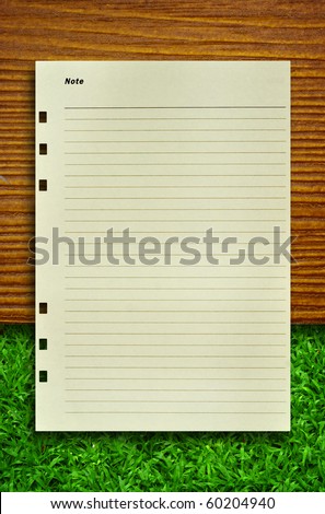 Note Paper on wood and grass for text an background
