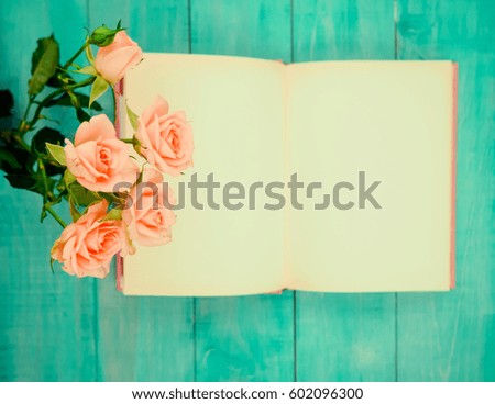 Vintage Roses Still Life. open notebook on a blue wooden background next to delicate roses, space for text