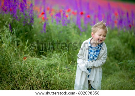Little boy laughing and having fun in a blooming spring field