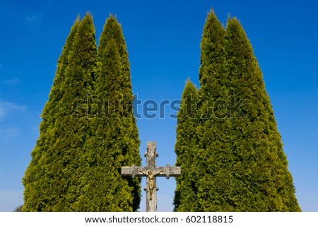 stone cross with a golden jesus between two trees