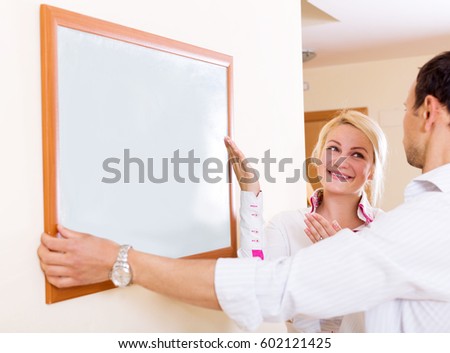 Cheerful couple drilling Wall to Hang picture frame