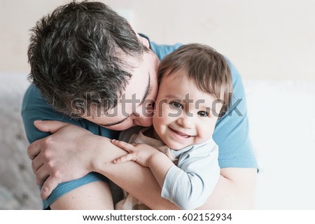 Close-up portrait of happy young father hugging and kissing his sweet adorable child. Indoors shot, concept image Royalty-Free Stock Photo #602152934